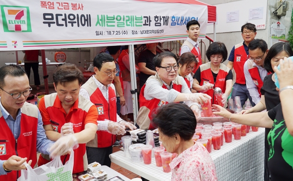 25일 서울 남산 쪽방촌에서 편의점 세븐일레븐 봉사단이 수박화채를 사람들에게 나눠주고 있다. (사진=세븐일레븐)