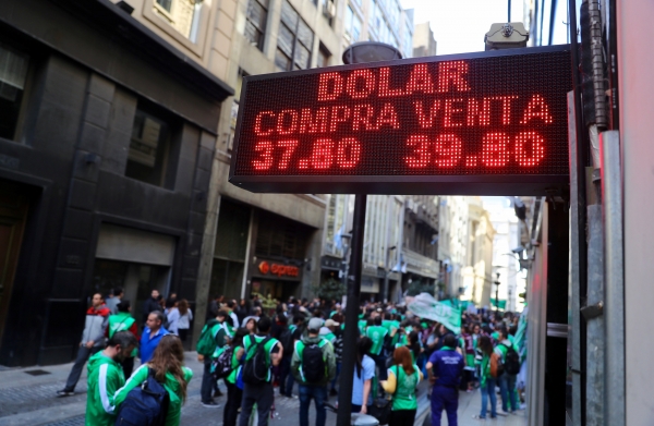 5일(현지시간) 부에노스아이레스 금융지구에 있는 환율 전광판 아래로 대량해고 반대 집회 행렬이 지나가고 있다. (사진=연합뉴스)