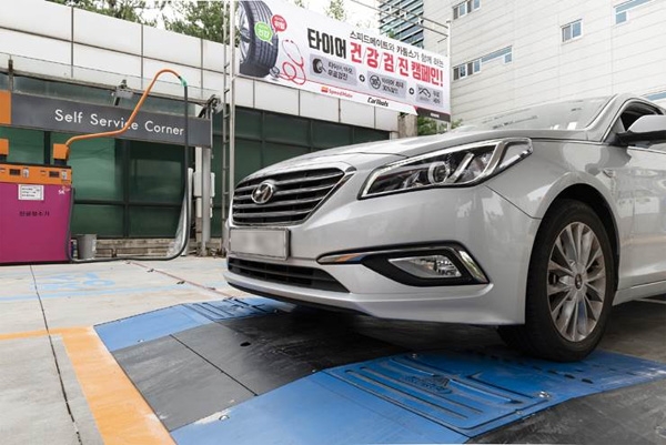 SK네트웍스의 종합 차량관리 브랜드 스피드메이트는 9월 20일부터 10월 말까지 '타이어 건강검진' 캠페인을 진행한다. 자동차가 바닥에 장착된 타이어 마모도 측정장비(파란색)를 통과하며 타이어 검진받는 모습. (사진=SK네트웍스)