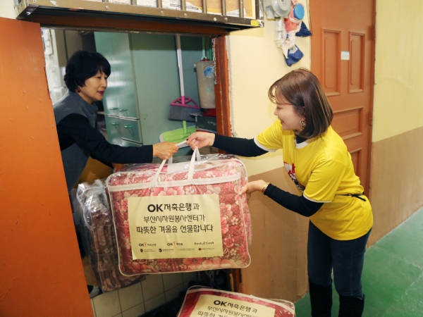 OK저축은행 관계사 직원들이 혹한기에 앞서 도움이 필요한 부산시 중구 지역 시민들에게 선물할 방한 키트를 배달하고 있다. (사진=OK저축은행)
