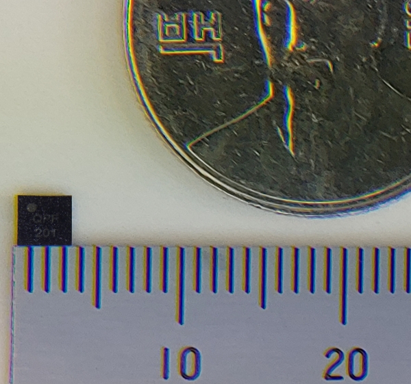이번에 개발된 IoT 단말용 초소형 양자보안칩과 100원짜리 동전의 크기를 비교하는 모습. (사진=LG유플러스)