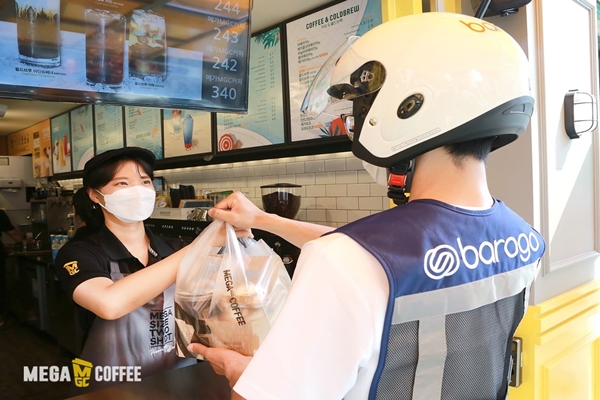 메가커피 직원이 바로고 직원에게 커피를 전달하고 있다. (사진=앤하우스)