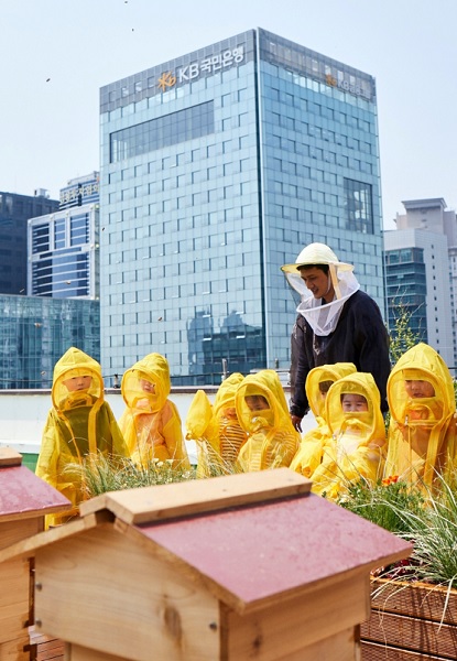 KB금융그룹 직원 가족들이 서울 여의도 KB국민은행 본점 옥상에 설치된 'K-Bee' 도시 양봉장에서 벌 키우기 체험활동에 참가하고 있다. (사진=KB금융그룹)