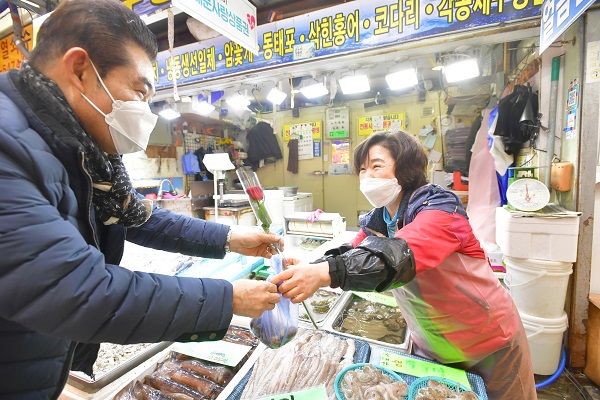 서울 서대문구 영천시장에서 한 상인(오른쪽)이 고객이 구입한 물건과 장미꽃 한 송이를 건네고 있다. (사진=)