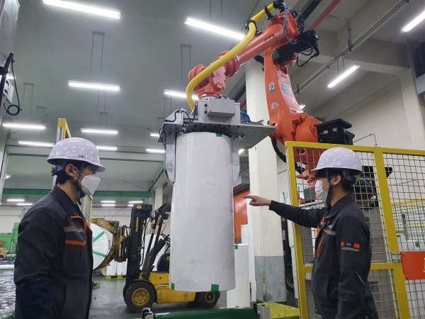 유진한일합섬 의령공장 직원들이 생산라인에 설치된 제조로봇을 가동하고 있다. (사진=유진그룹)