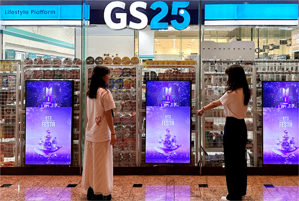 편의점 GS25 앞에서 여성들이 '2023 BTS 페스타' 홍보물을 살펴보고 있다. (사진=GS리테일) 